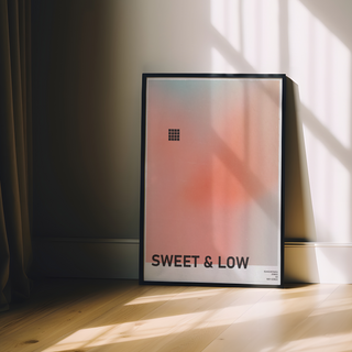 Urban typography poster with gradient peach design and text 'SWEET & LOW'. Displayed in a black wooden frame.