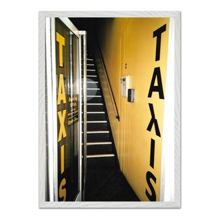 Urban 35mm film photograph of a taxi service front door with an edgy street art aesthetic, displayed in a premium white wooden frame.