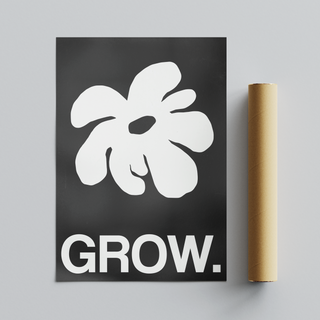 Framed artwork featuring a white abstract leaf design and the word 'GROW.' on a black background. Placed next to cardboard tube packaging.