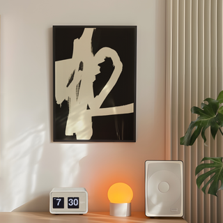 Painted black and white abstract brush mark art print. White brush marks on black background. Displayed in a black wooden premium frame. Place on a bedroom wall next to plant, speakers and lamp.