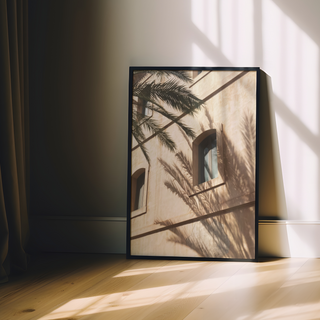 Framed photograph of a minimalist white building with palm tree shadows cast across the surface, displayed in a premium black wooden frame — perfect for modern coastal and urban interiors