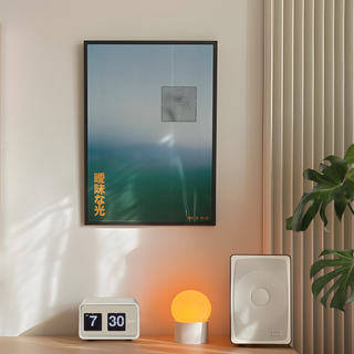Framed hazy light blue abstract artwork on a wall with a small clock and lamp below