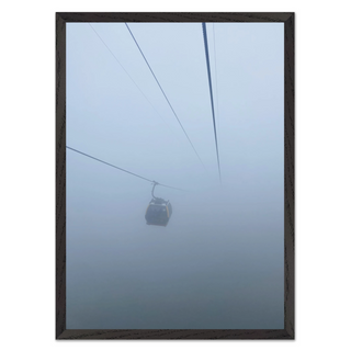 Framed photograph capturing a cable car in misty, foggy conditions, displayed in a premium black wooden frame.
