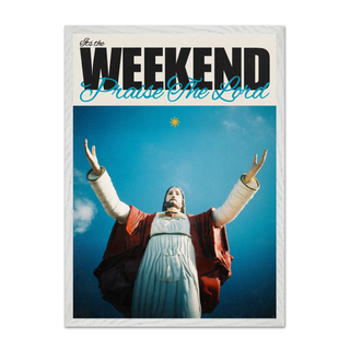 Bold typography poster with a religious figure Jesus with arms outstretched against a blue sky, text 'It's the Weekend Praise The Lord' at the top. Displayed in a premium white wooden frame. 