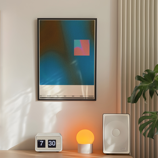 Abstract blue and pink wall art with typography. Displayed in a black wooden frame. Placed in a minimalistic decor room with a plant, lamp and speakers. 
