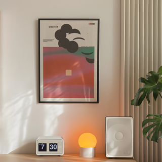 Abstract poster with pink and green hues, bold typography reading ‘Gravity’ on a clean white background. Placed on a wall in a bedroom next to plant, lamp and speakers. 